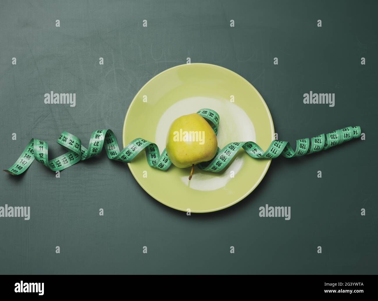 Reifer Apfel mit einem Zentimeter auf einem grünen Hintergrund gewickelt, Körpergewichtskontrolle Konzept Stockfoto