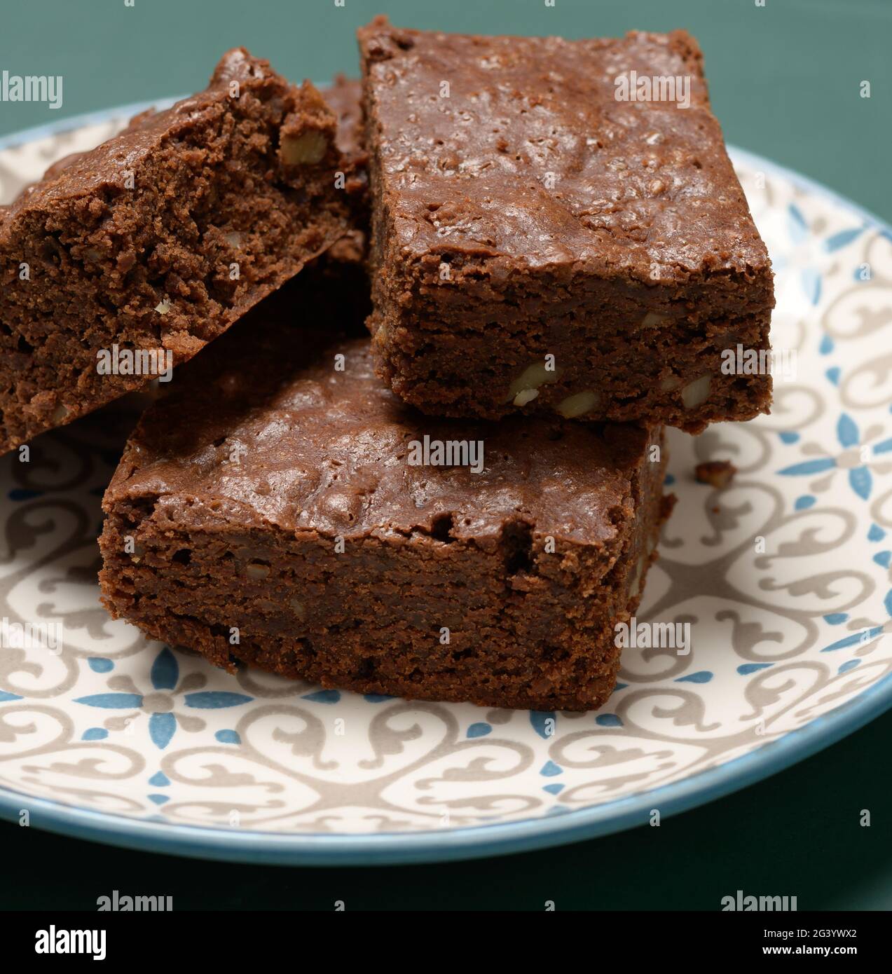 Gebackene quadratische Stücke Brownie Walnuss Schokoladenkuchen liegen auf einem runden Teller Stockfoto