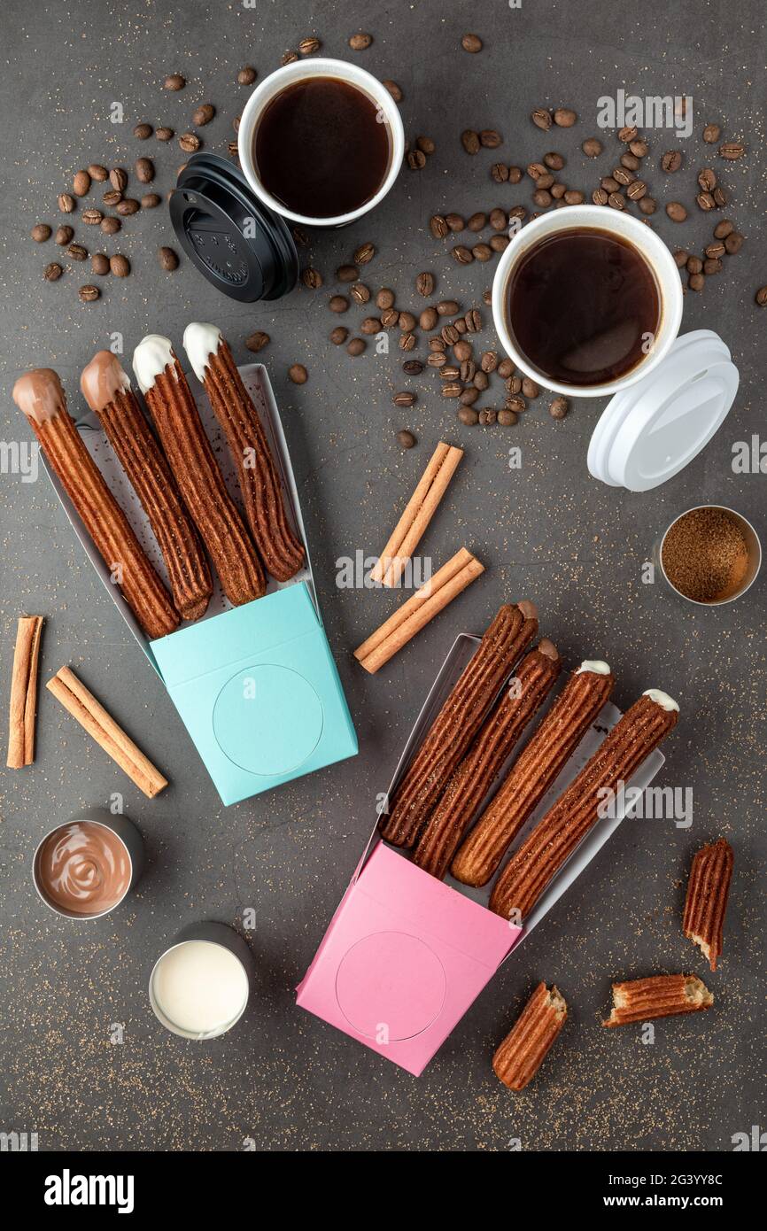 Blick von oben auf Kaffee zum Mitnehmen neben Schokolade gefüllt und einfache Churros. Stockfoto