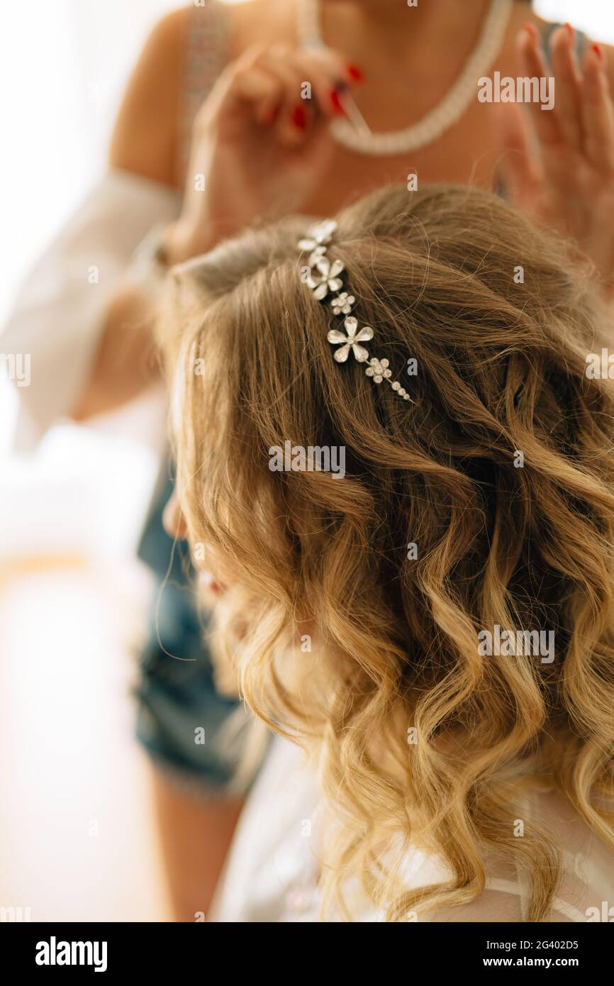 Stylistin legt eine Haarnadel in der Frisur der Braut während Hochzeitsvorbereitungen Stockfoto
