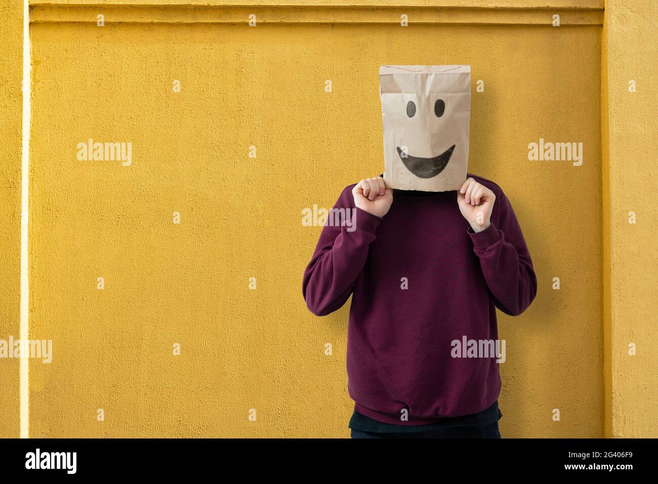 Person mit Papiertüte auf dem Kopf mit einem Lächeln, glückliches Erfolgskonzept Stockfoto