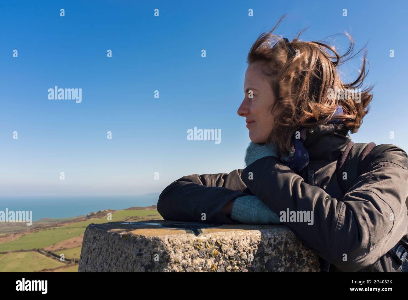 Braunhaarige Frau an einem windigen Aussichtspunkt an der Küste. Stockfoto