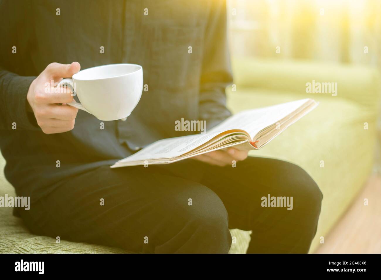 Person, die sich zu Hause entspannt, Buch liest und Tee trinkt, sich am Abend ausruhen Stockfoto