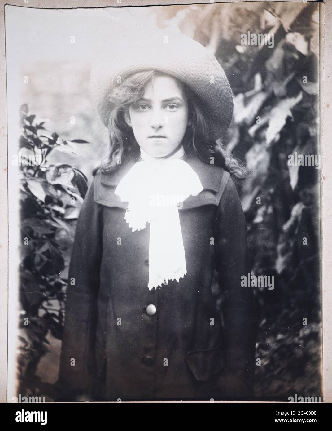 Ein authentisches Vintage-Foto der 1910er Jahre von einer jungen Frau, die einen Hut im Garten trägt. Konzept der Individualität, Nostalgie, Anfang des 20. Jahrhunderts Stockfoto