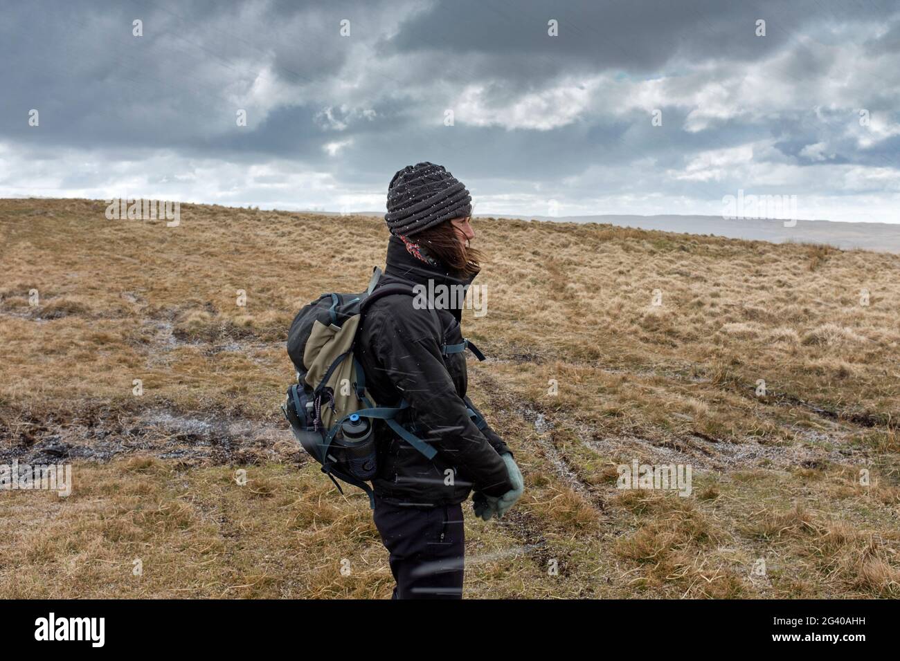 Frau, die bei einem Hagelsturm in Wales auf dem Hügel herumläuft. Stockfoto