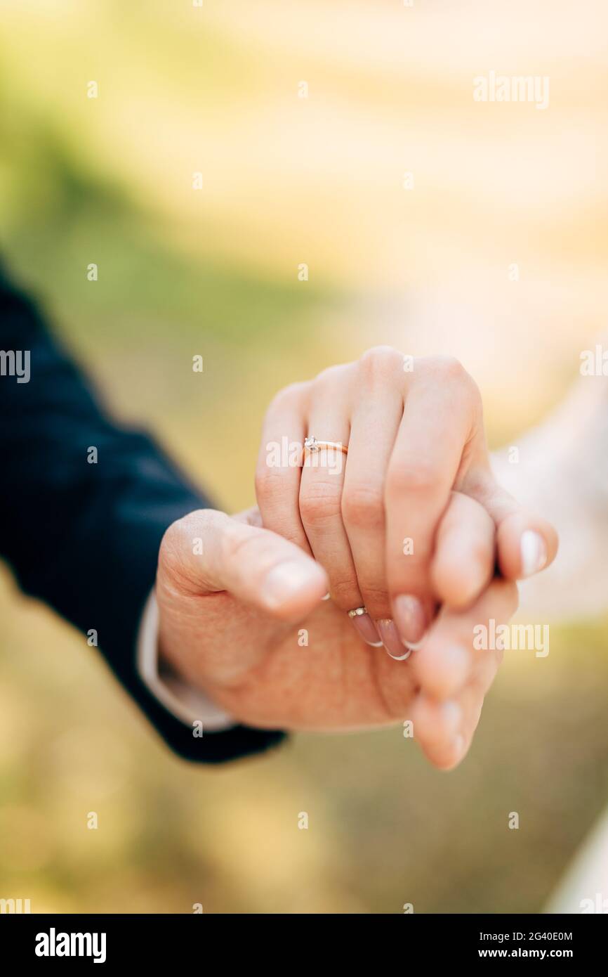 Hände von Bräutigam und Braut halten zusammen Stockfoto