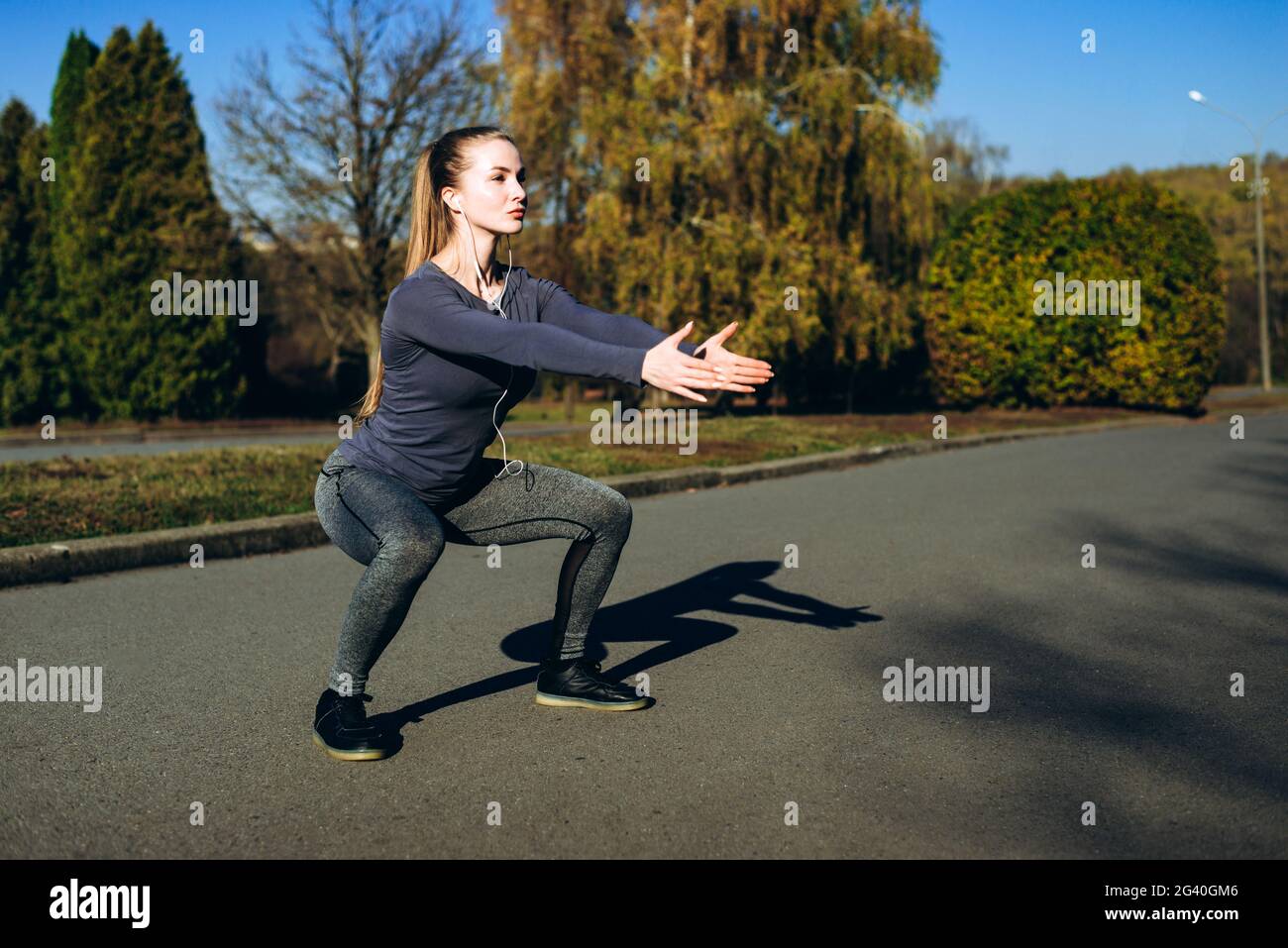 Mädchen in Sportbekleidung und Kopfhörern machen Sit-Ups beim Training im Freien. Stockfoto