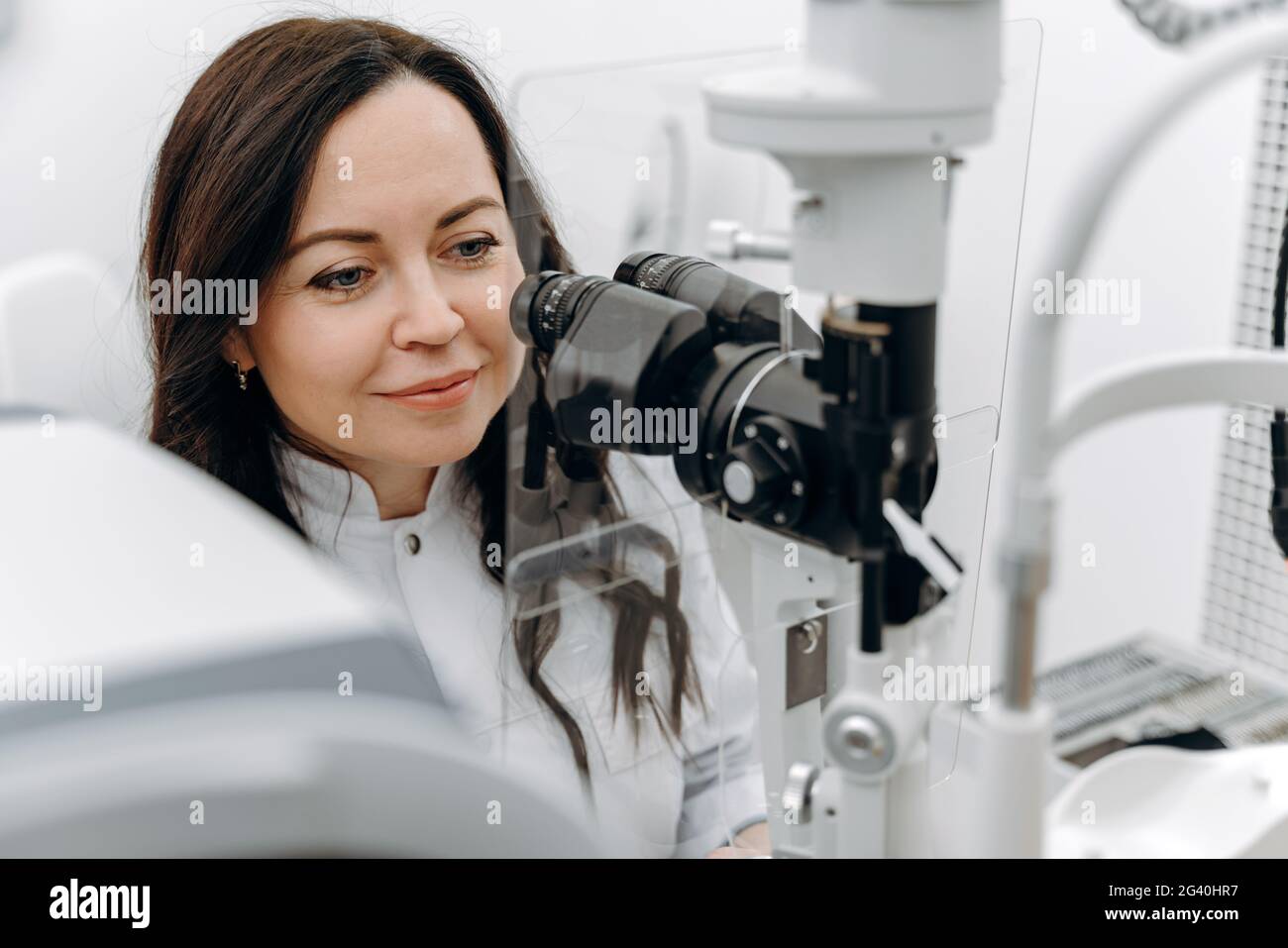 Junge schöne Frau Arzt / Augenarzt / Optiker in einer ophthalmologischen Klinik untersucht einen Patienten mit Mikroskopie. Stockfoto