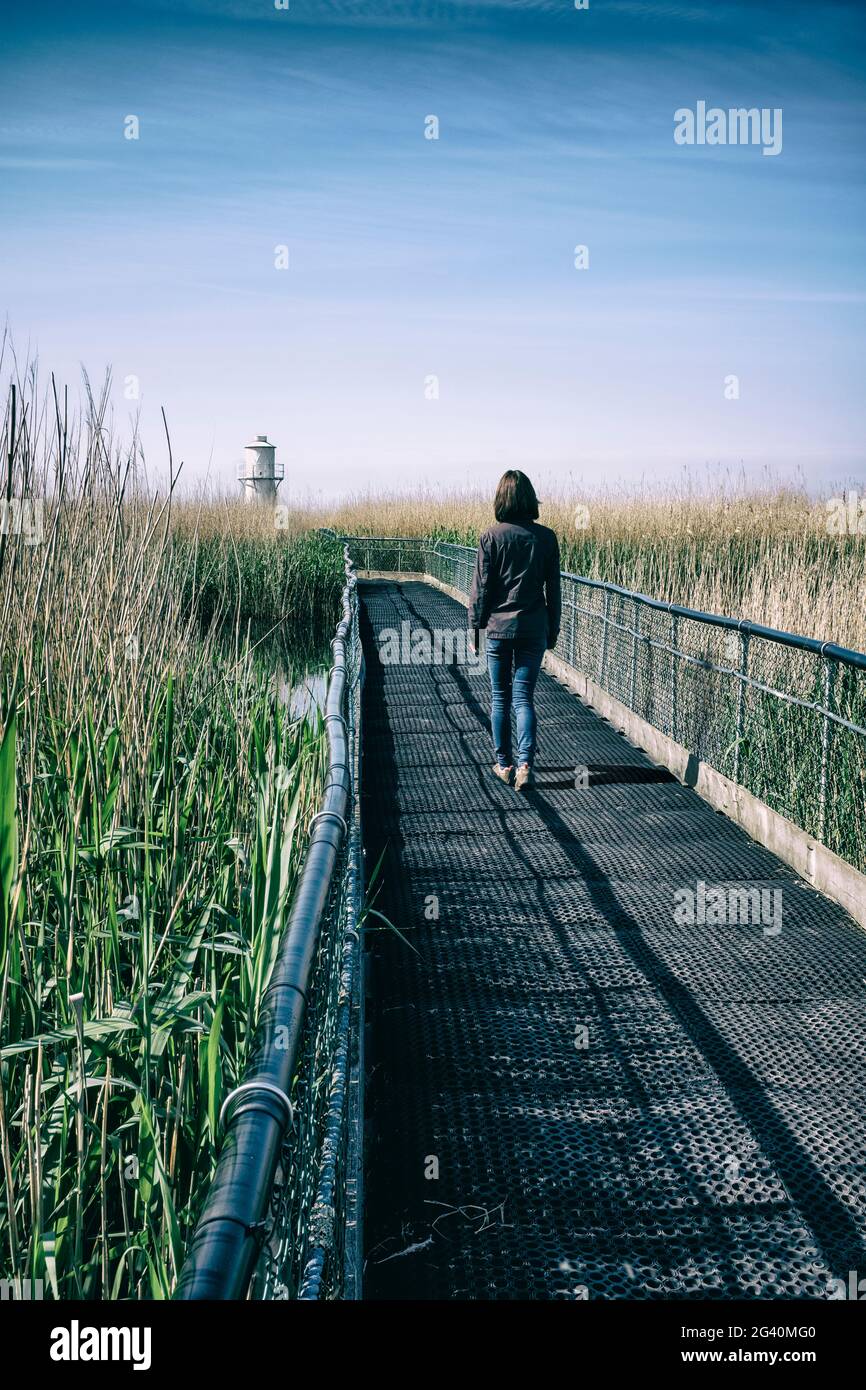 Frau auf einer Brücke in der Nähe eines Leuchtturms. Stockfoto