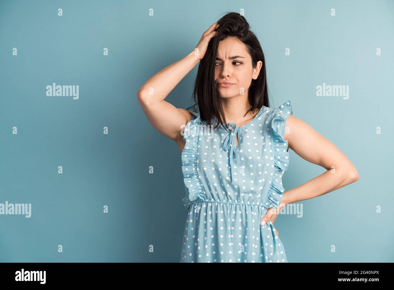 Verwirrt Frau denken, Blick beiseite isoliert blaue Wand Hintergrund kopieren Raum über Kopf. Menschliche Ausdrücke Emotionen Gefühle Körpersprache Stockfoto