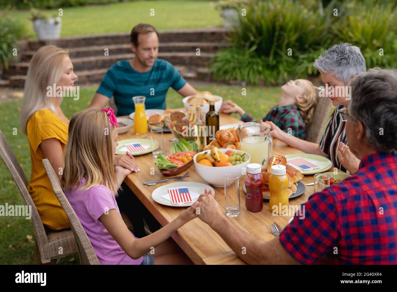 Kaukasische drei-Generationen-Familie hält Hände sagen Gnade vor dem Essen Gemeinsames Essen im Garten Stockfoto