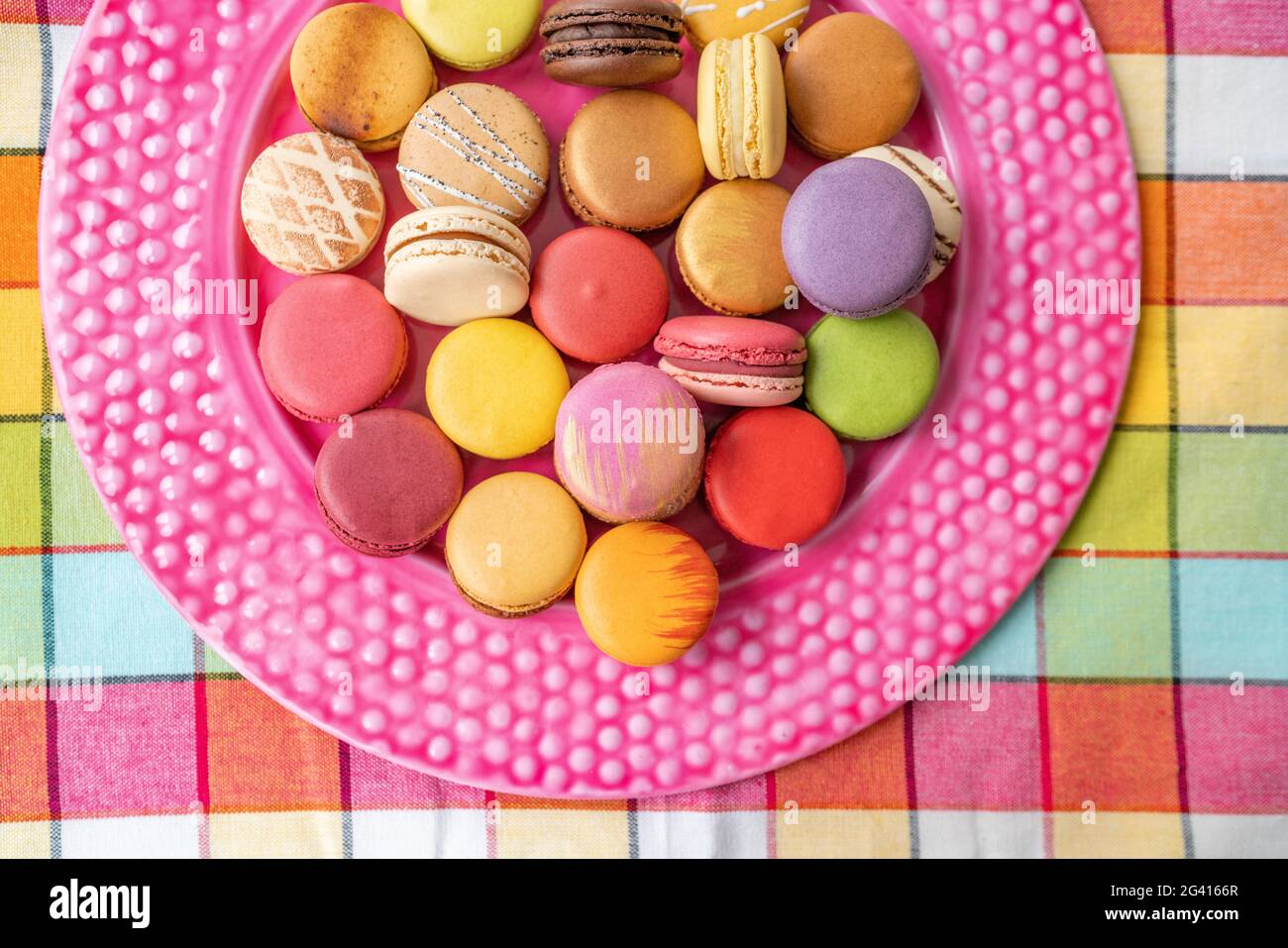Viele französische Macarons Auswahl an farbenfrohem Gebäck auf rosa Dessertplatte Draufsicht. Retro Vintage Wohnküche Hintergrund. Auswahl an ausgefallenen Gebäckstücken Stockfoto