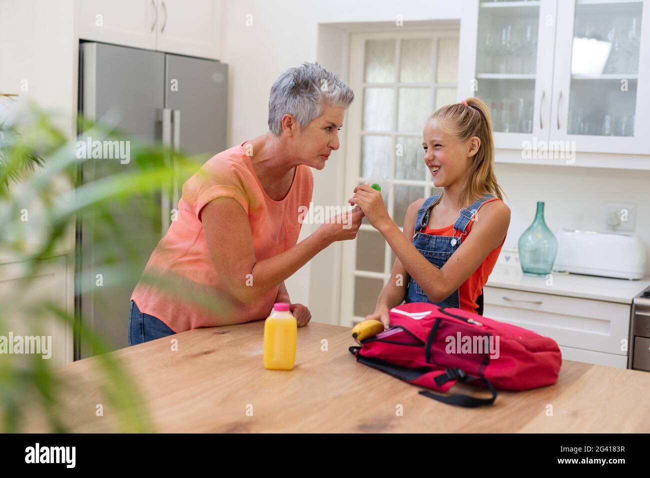 Ältere Großmutter gab der Enkelin ein Lunchpaket und Lutscher in der Küche Stockfoto