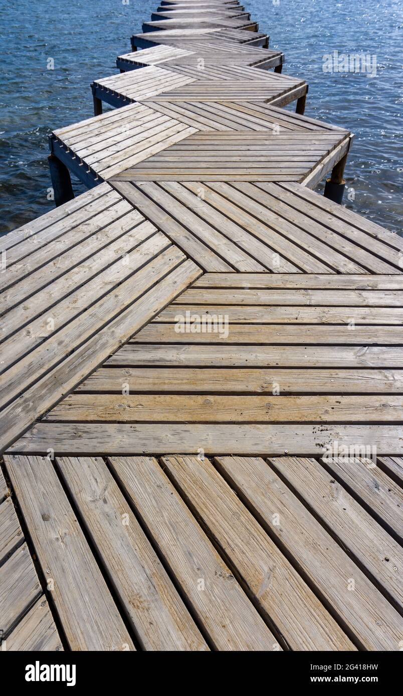 Nahaufnahme eines abstrakten Winkels auf eine hölzerne Promenade und einen Pier, der in den Ozean führt Stockfoto