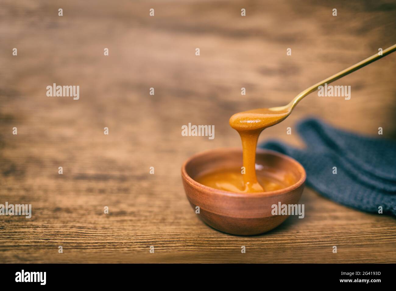 Manuka Honig rohe organische Flüssigkeit aus Manuka Blumen in Neuseeland. Gesunde antibakterielle antimykotische Eigenschaft Blume. Auf braunem Holzhintergrund Stockfoto