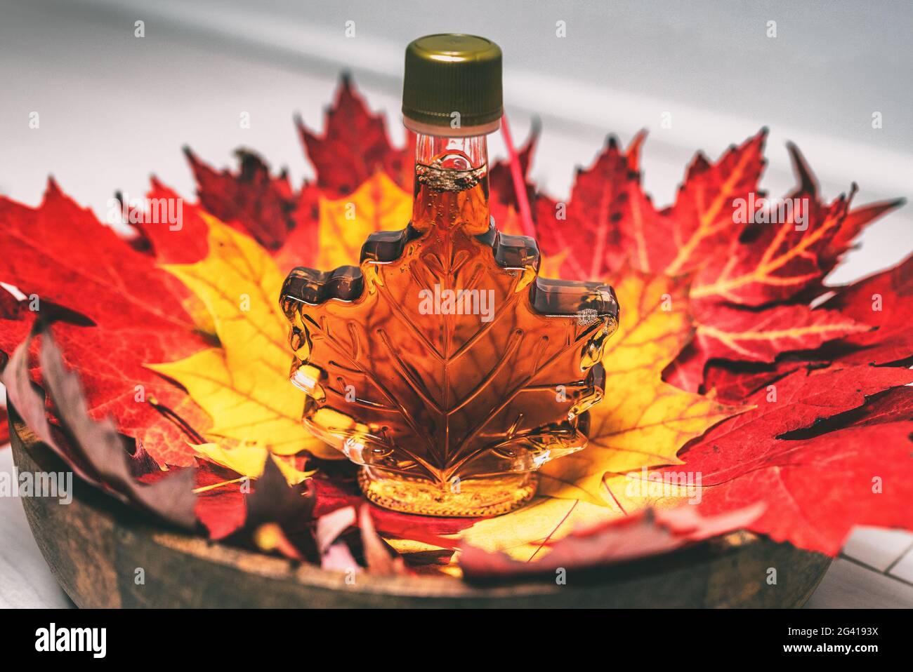 Ahornsirup Flasche in roten Ahornholzblättern für Touristen Geschenk Souvenir. Kanada gibt eine bernsteinsüße Flüssigkeit aus der Zuckerhütte in Quebec an Stockfoto