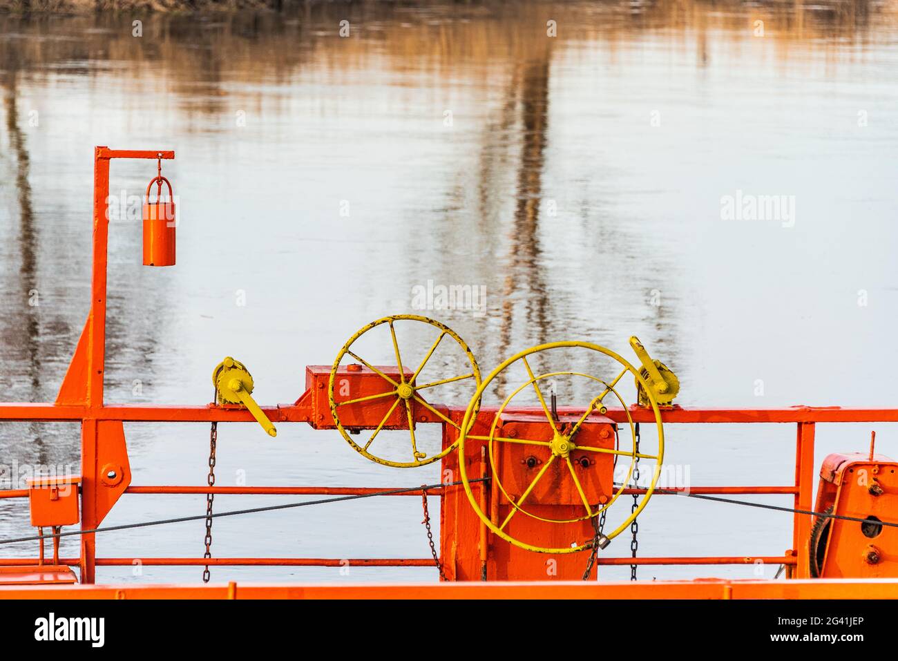 Die Details der Seilfähre, die über einen Fluss durch Kabel verbunden mit beiden Ufer. Die orange Kettenfähre, gelbes Lenkrad und blaues Wasser Stockfoto