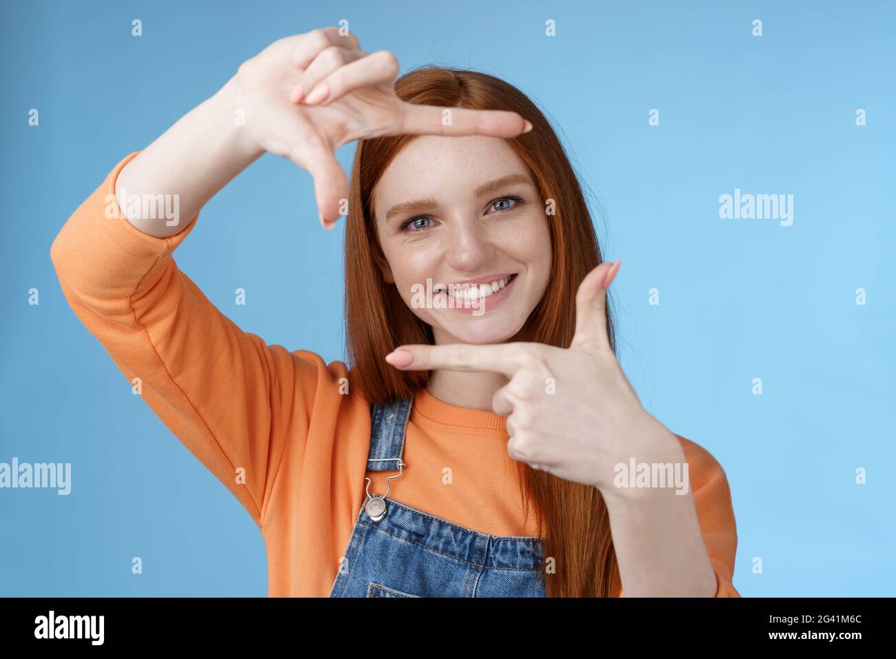 Kreative gut aussehende schöne rothaarige weibliche Assistentin Suche Inspiration lassen Handrahmen durch erfreut lächelnd satisfi aussehen Stockfoto
