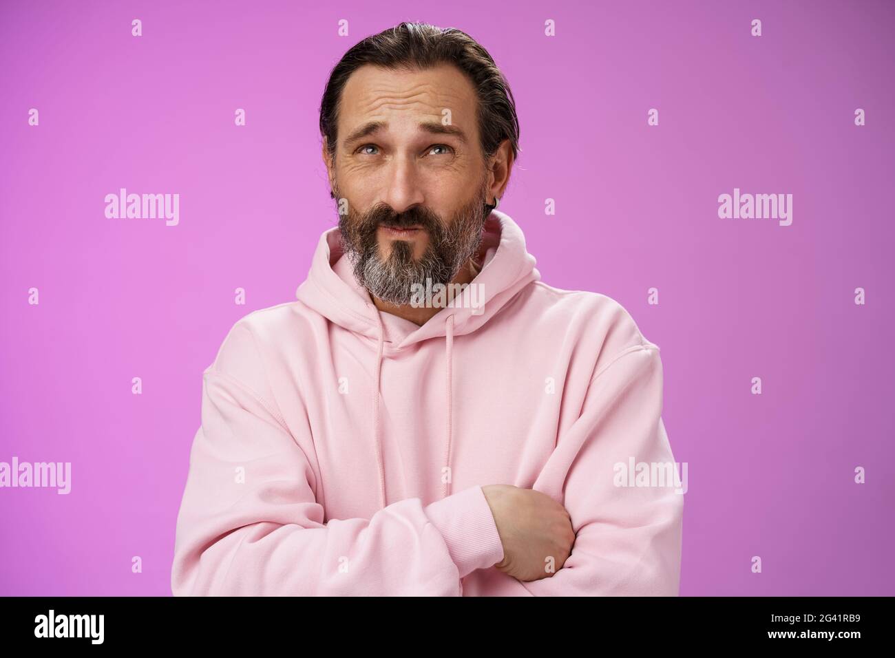 Unsicher beunruhigt kaukasischen bärtigen erwachsenen Kerl mit Ohrring rosa Kapuzenpullover drücken Lippen runzelnd zählen Geist stehen zögerlich Doubltfu Stockfoto