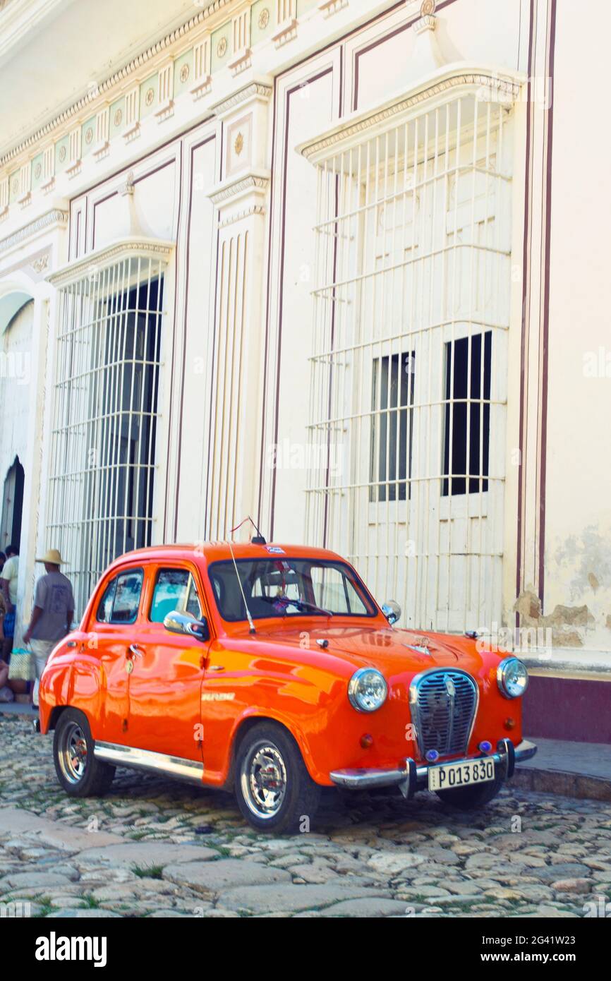 Klassisches rotes Auto vor einem weißen Gebäude in Trinidad, Kuba Stockfoto
