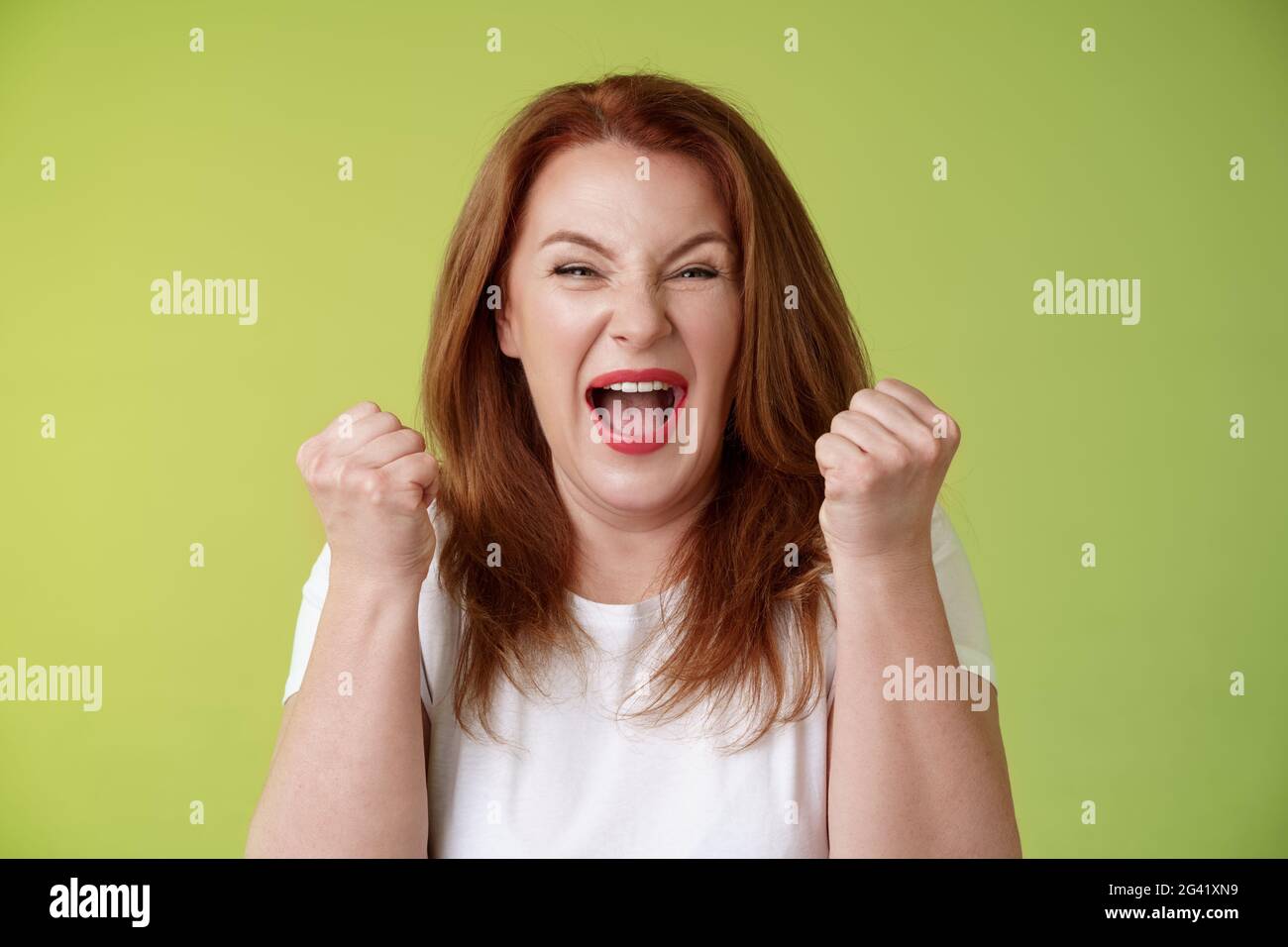 Ja, wir haben es gemacht. Fröhliche glücklich Rotschopf mittleren Alters weibliche Gewinnerin Pumpe Fäuste Feier Erfolg Geste brüllen Triumph Freude smi Stockfoto