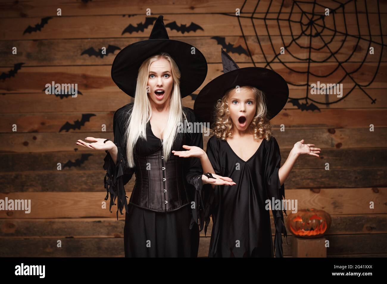 Halloween Konzept - fröhliche Mutter und ihrer Tochter in Hexe Kostüme mit etwas schockierend. Stockfoto