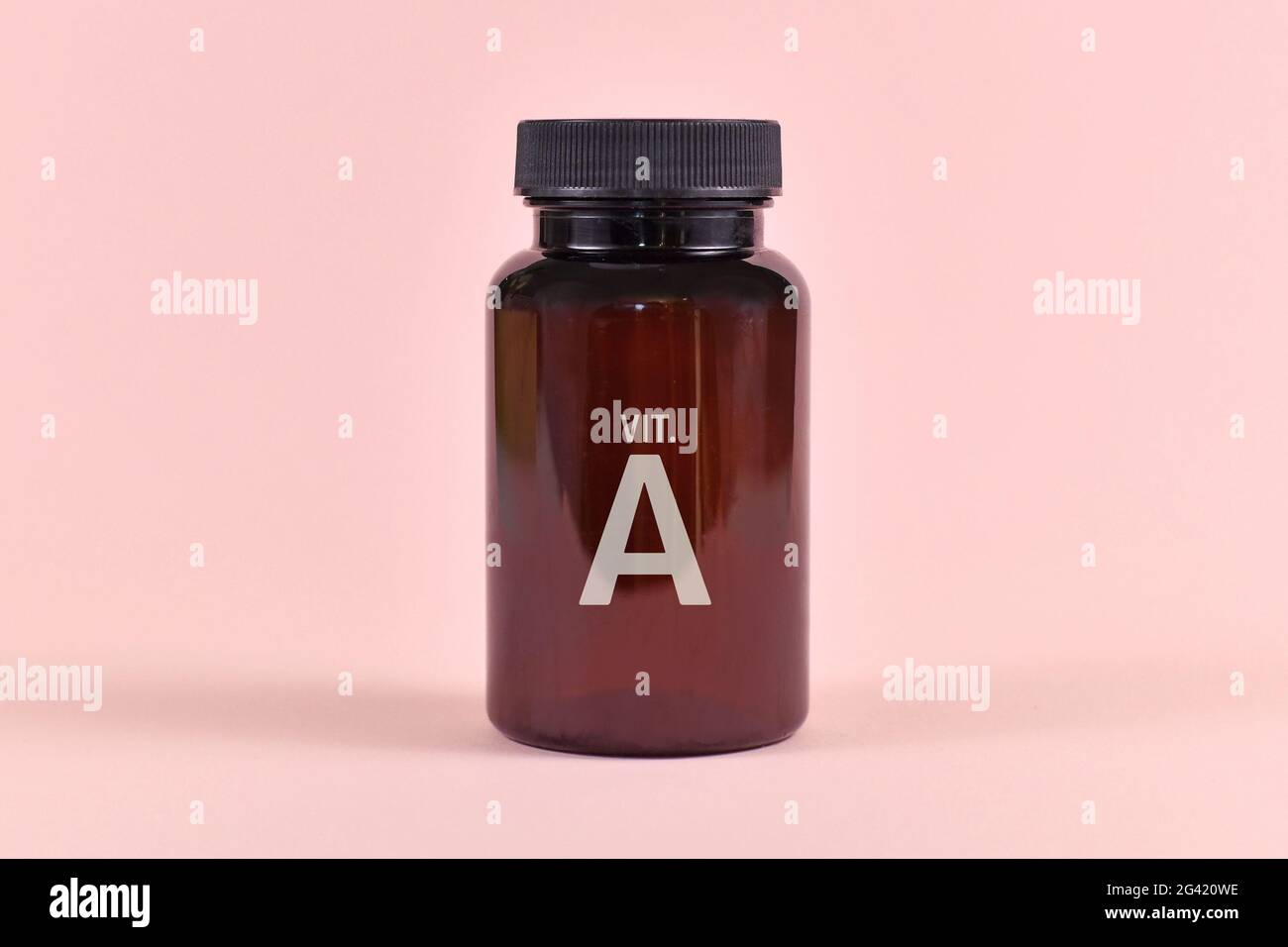 Medikamentenflasche mit Vitamin A Beschriftung auf rosa Hintergrund Stockfoto