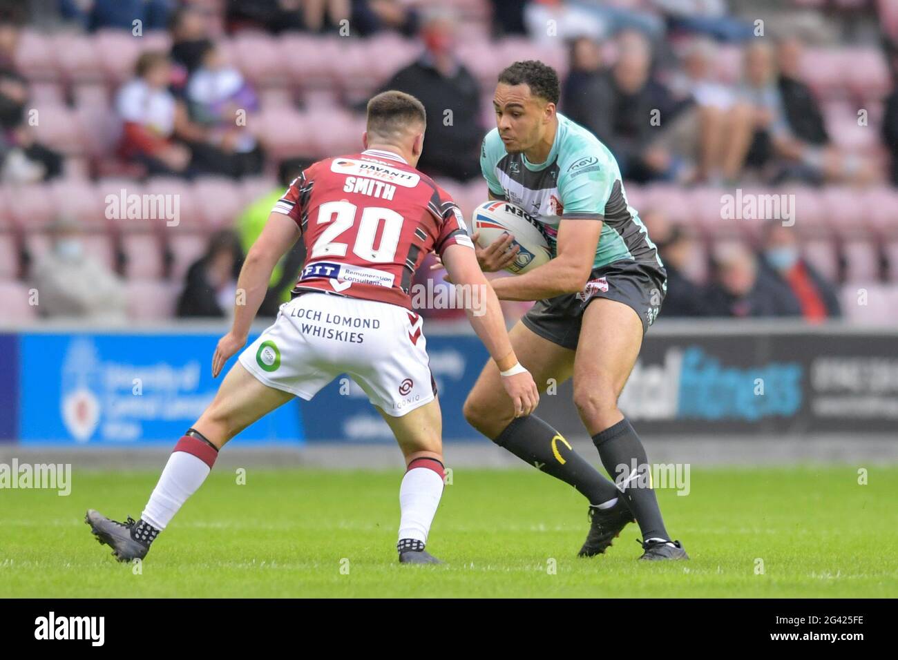 Luis Johnson (27) von Hull KR sucht einen Weg hinter Harry Smith (20) von Wigan Warriors Stockfoto