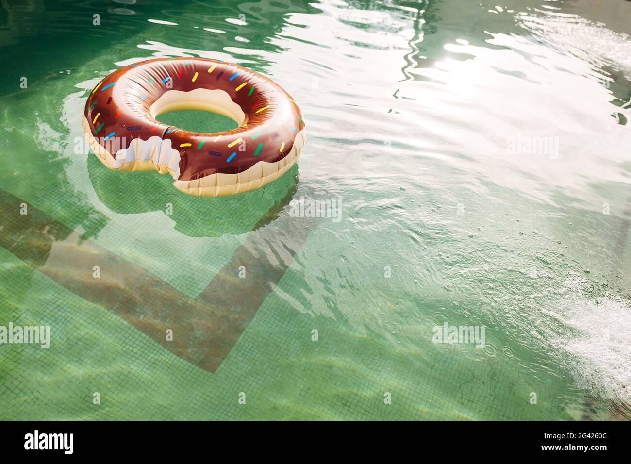 Im Wasser des Pools schwimmt ein Schwimmkreis in Form eines gebissenen Donuts. Stockfoto