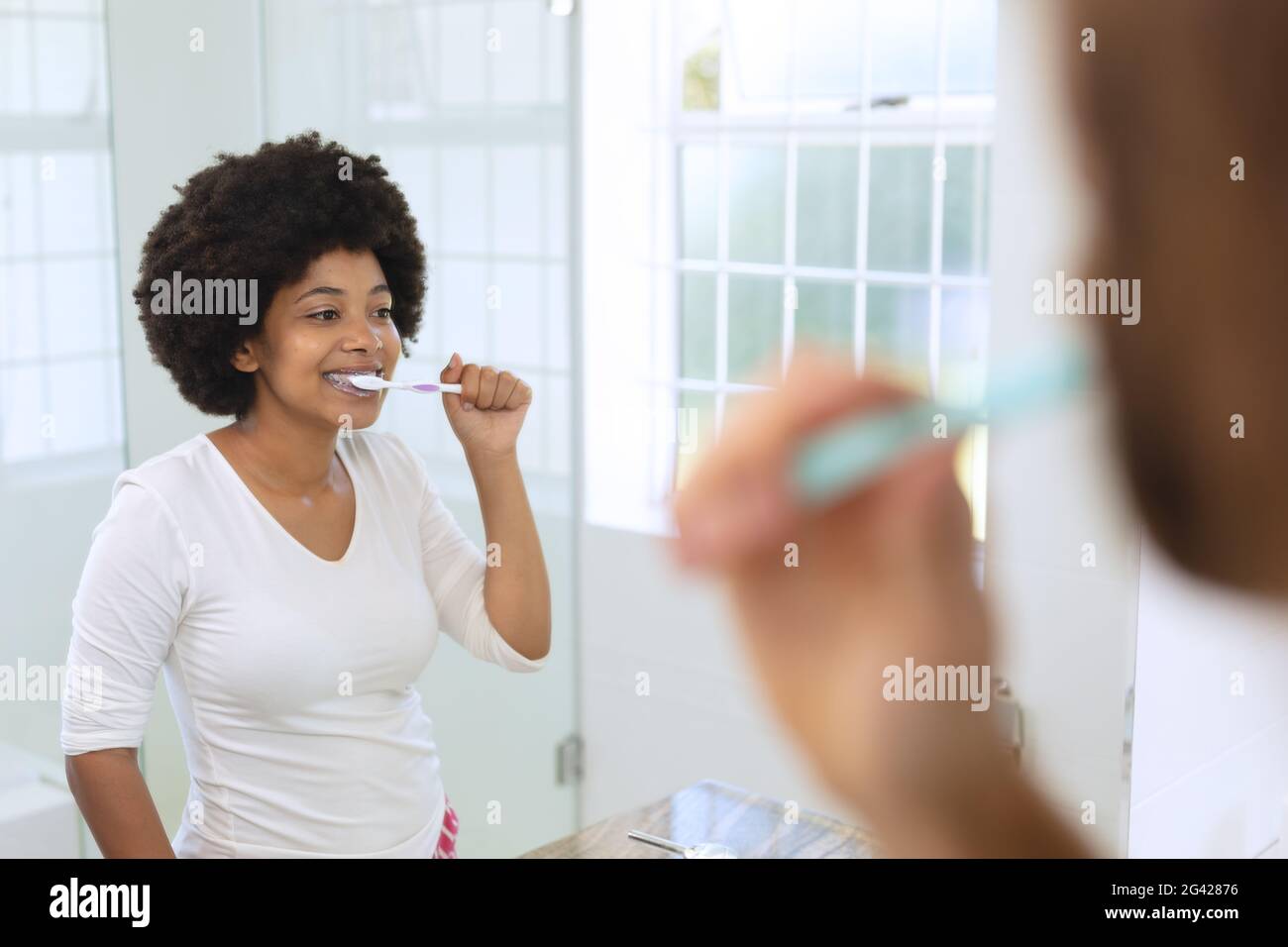 afroamerikanische Frau, die im Badezimmer steht und Zähne putzt Stockfoto