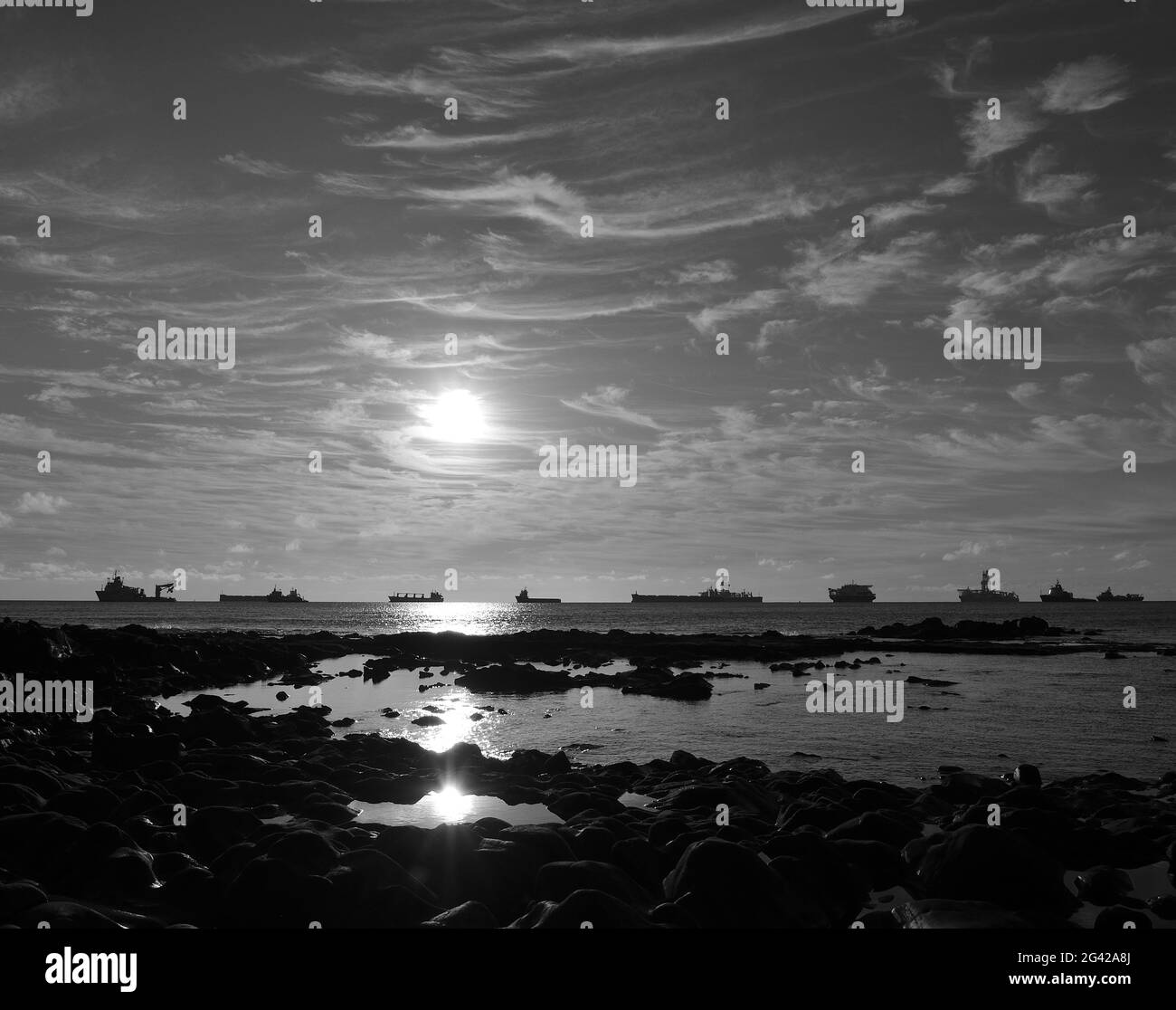 Sonnenaufgang von der Küste und Schiffe am Horizont, Schwarz-Weiß-Modus Stockfoto