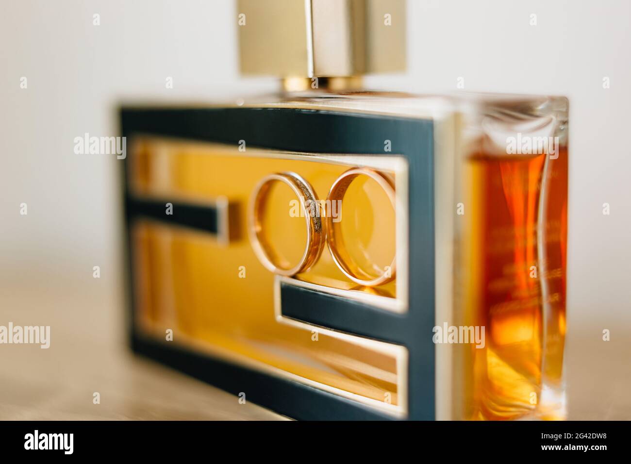 Goldene Eheringe der Braut und des Bräutigams auf einer Flasche Parfüm. Stockfoto