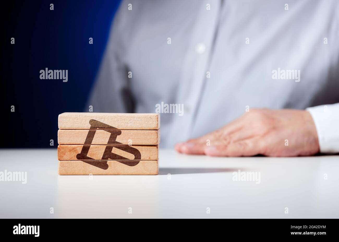 Auf Holzblöcken geschnitztes Gavel-Symbol mit einem Mann, der im Hintergrund sitzt. Recht, Gerechtigkeit oder Auktionskonzept. Stockfoto