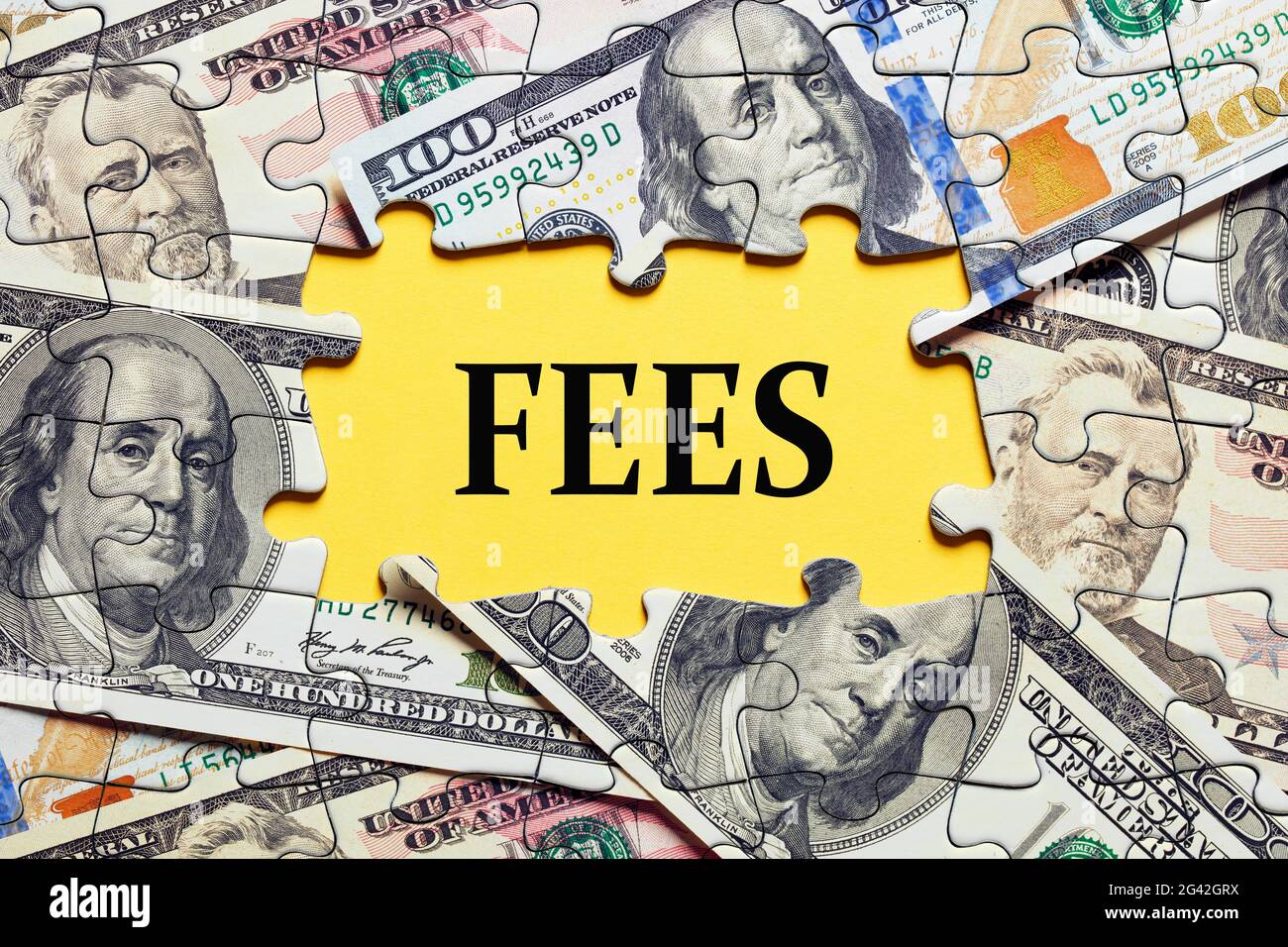 Das Wort Gebühren von Puzzleteilen mit Dollar-Geldschein umgeben. Geschäfts- und Finanzierungskonzept für Kosten, Gebühren, Provisionen oder Strafen. Stockfoto