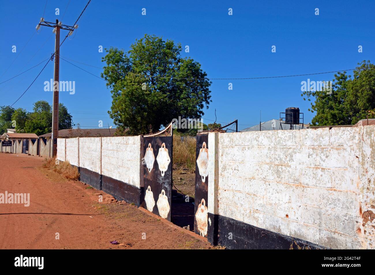 Gambia; Central River Region; Kuntaur; an der Hauptstraße; Mauer mit Eingangstor zu einem privaten Grundstück Stockfoto