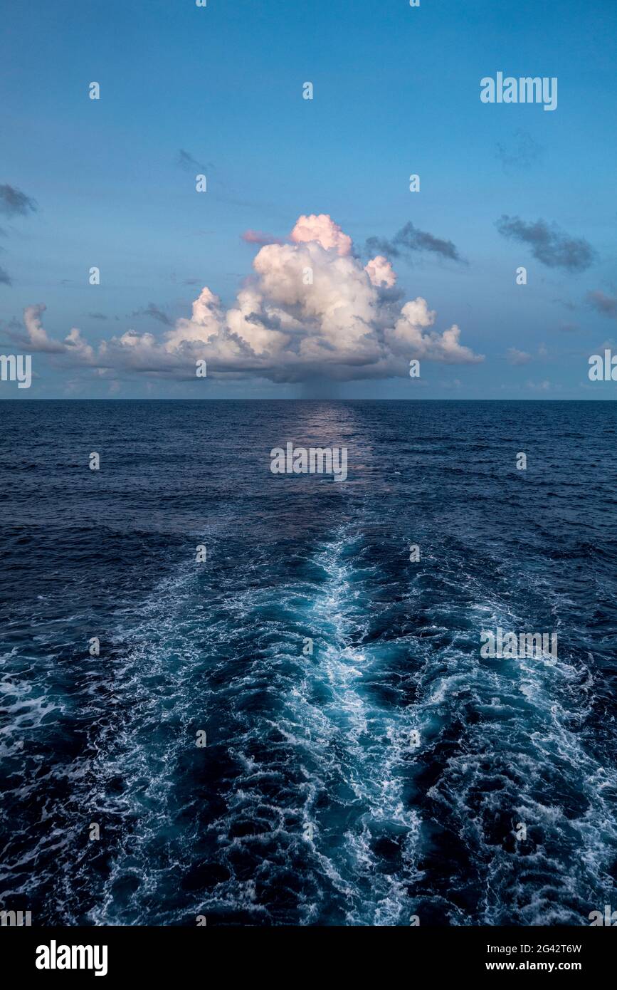 Wellen hinter dem Passagierfrachtschiff Aranui 5 (Aranui Cruises) mit einer majestätischen Wolke am Horizont, auf See zwischen den Marquesas-Inseln und den Tuamotu Stockfoto