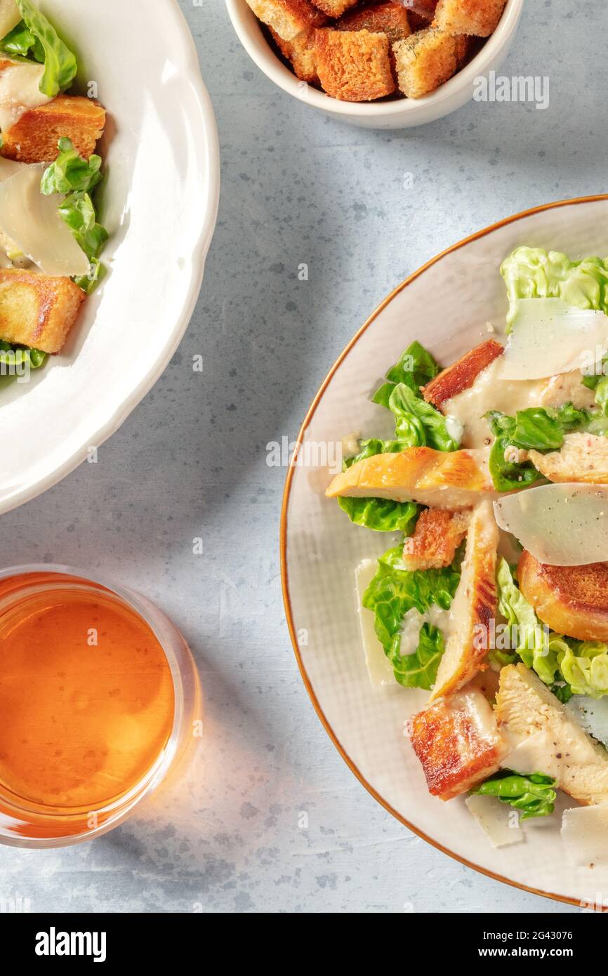 Hähnchen Caesar Salat mit Wein, über Kopf Schuss von zwei Platten Stockfoto