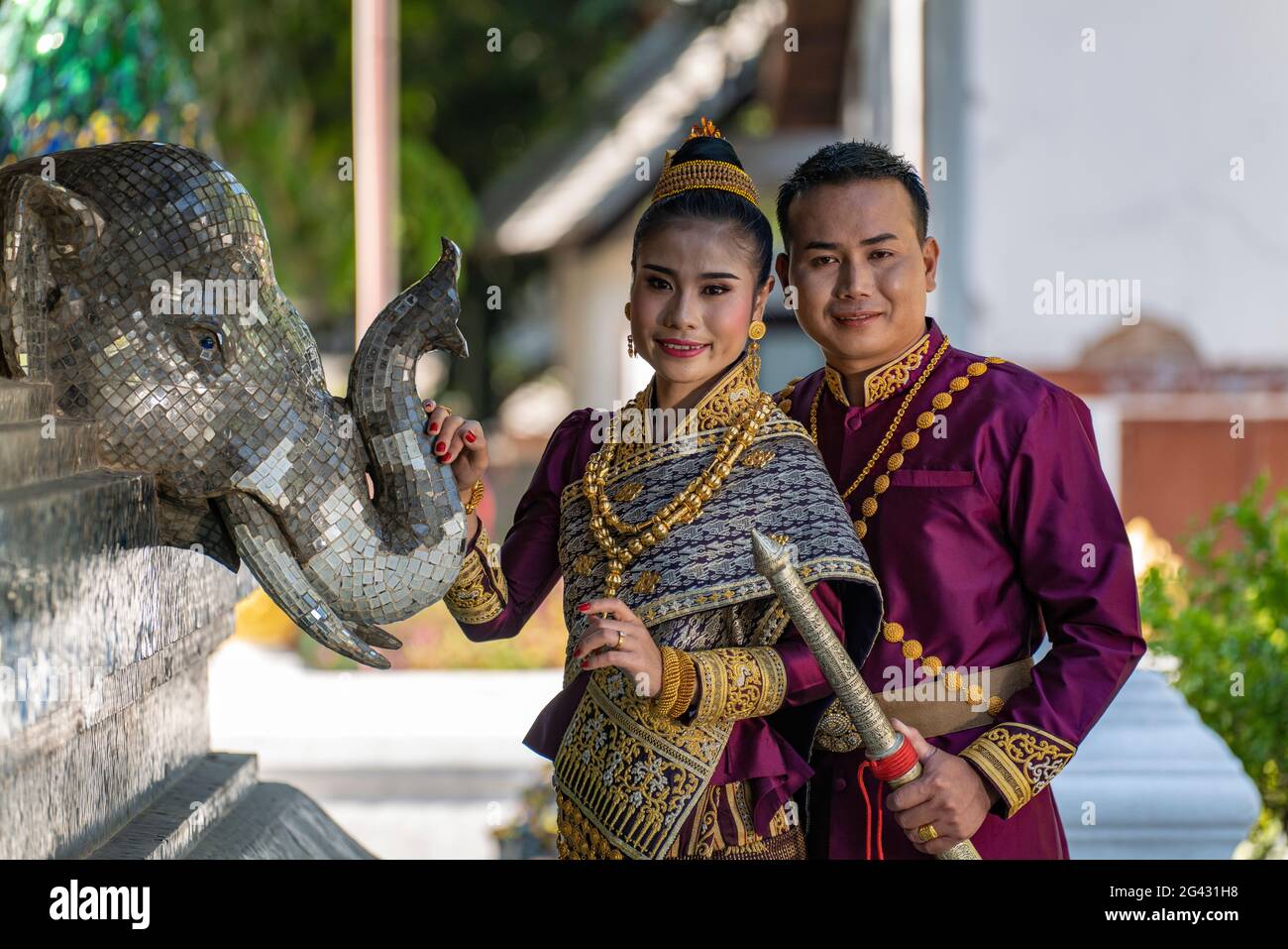 Glückliches Brautpaar in wunderschöner laotischer Hochzeitskleidung während des Fotoshootings im Wat Xieng Thong Tempel, Luang Prabang, Provinz Luang Prabang, Laos, Asi Stockfoto