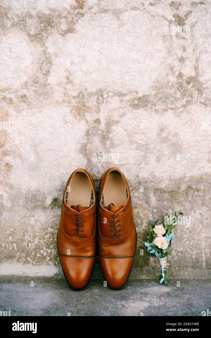 Braune Schuhe für einen Mann und einen Bräutigam boutonniere. Stockfoto