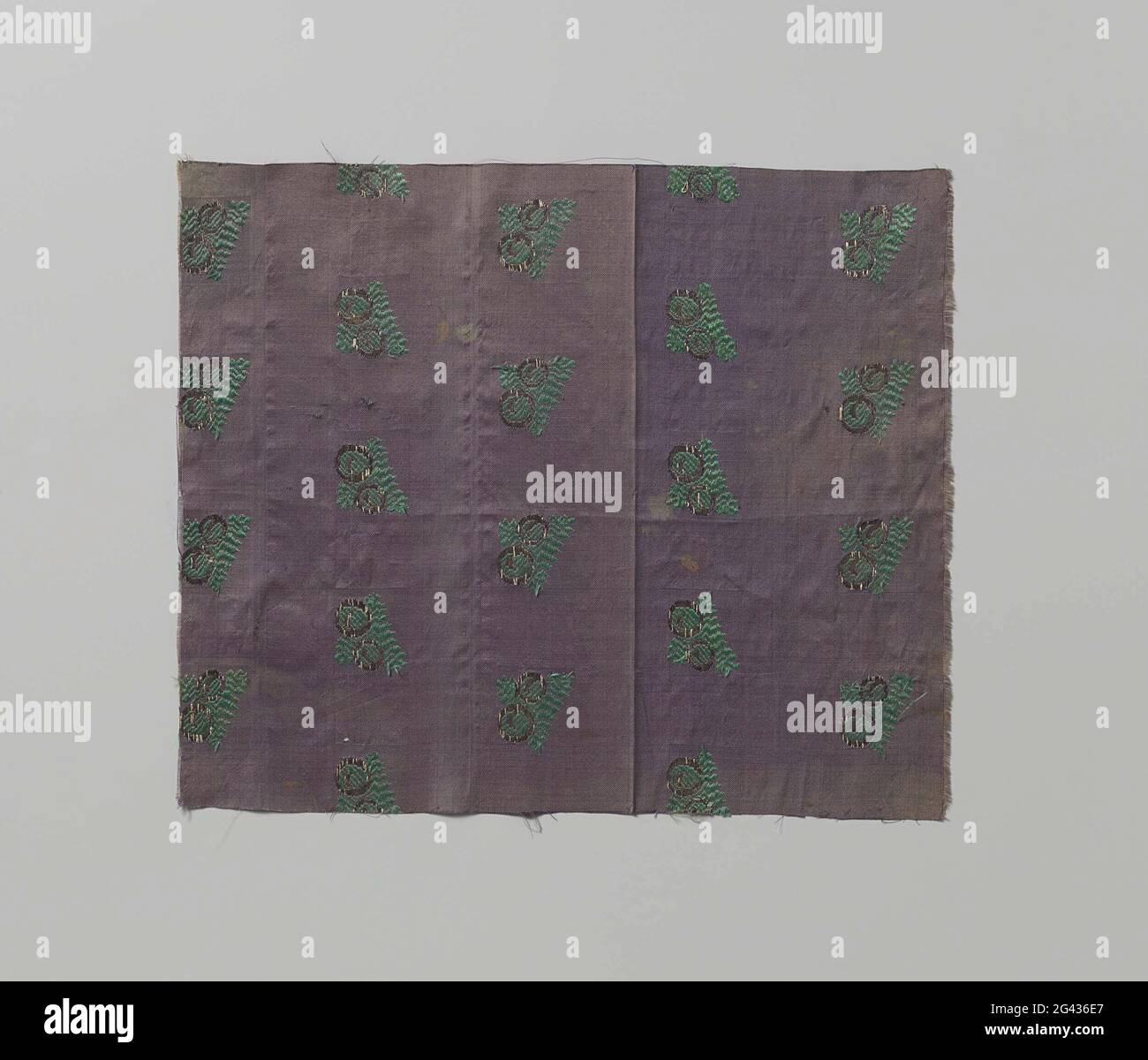 Fragment der brochierten Seide. Fragment Seidengewebe mit einem violetten Boden, auf dem ein Muster von Reihen stilisierter Blätter (Stechpalme?) Mit Früchten in Grün und Silber. Stockfoto