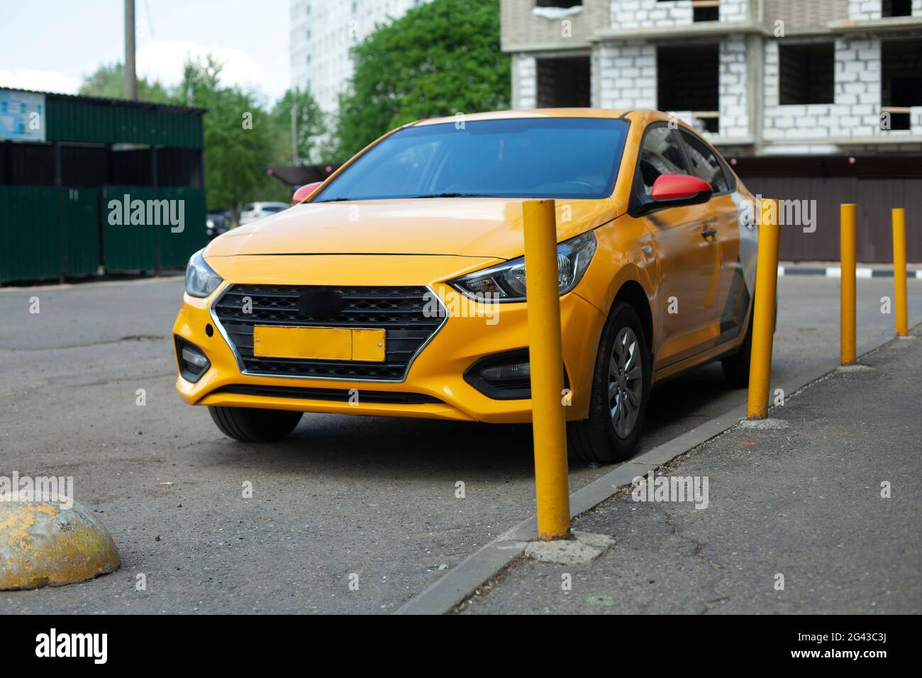 Taxi auf dem Parkplatz. Vor dem Haus steht ein gelbes Auto. Das Taxi wird in die Nähe der gelben Pfosten geworfen. Warten auf das Auto. Stockfoto