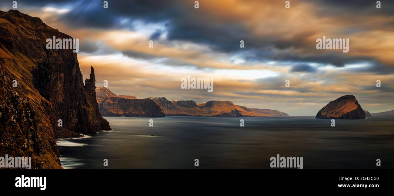 Küstenlandschaft mit Hexenfinger-Felsen und der Insel Koltur bei Sonnenuntergang, Färöer-Inseln, Dänemark Stockfoto