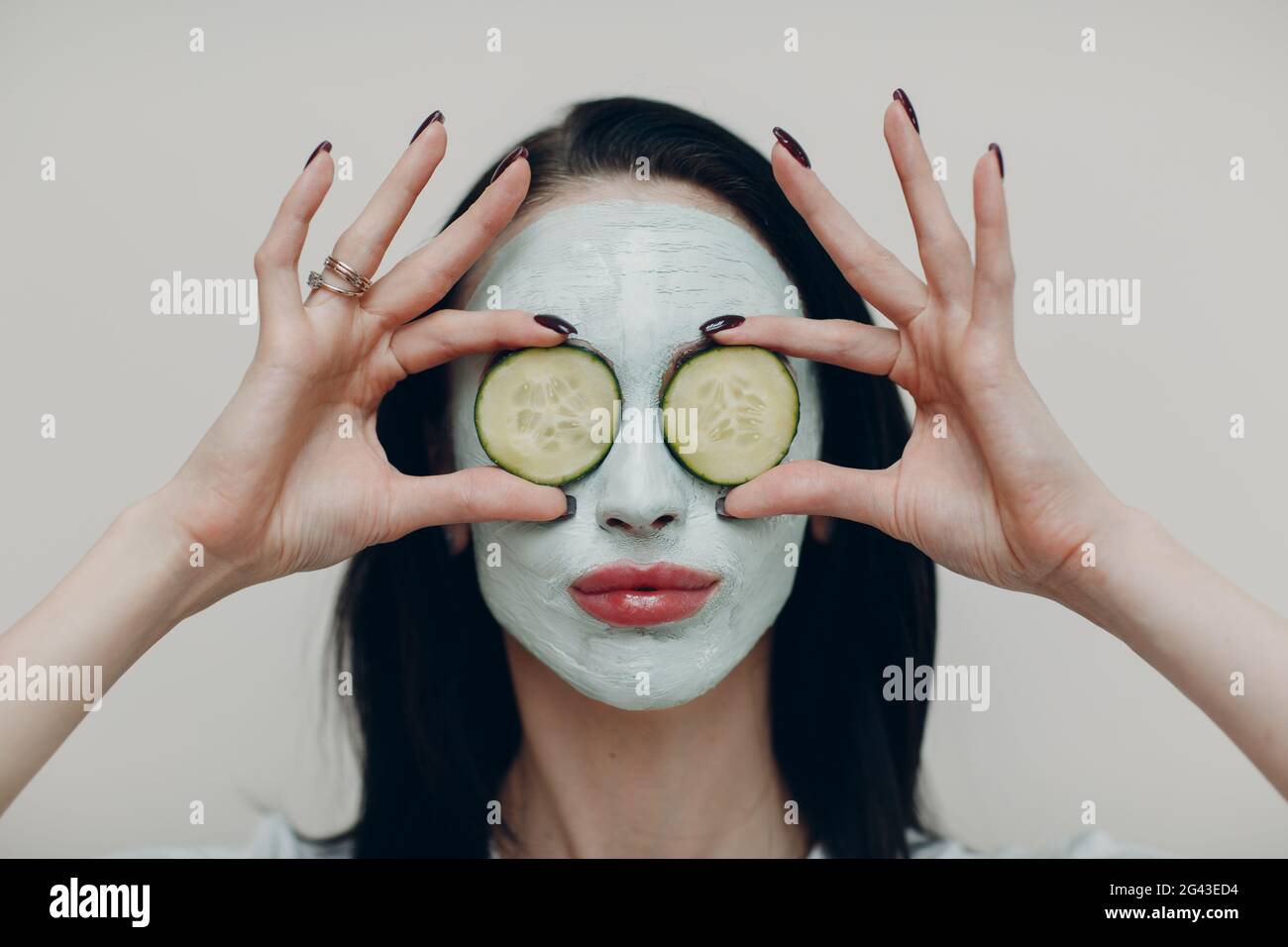 Junge schöne Frau Porträt erhalten Gesichtsmaske Ton mit Gurke auf den Augen in Spa Schönheitssalon Stockfoto