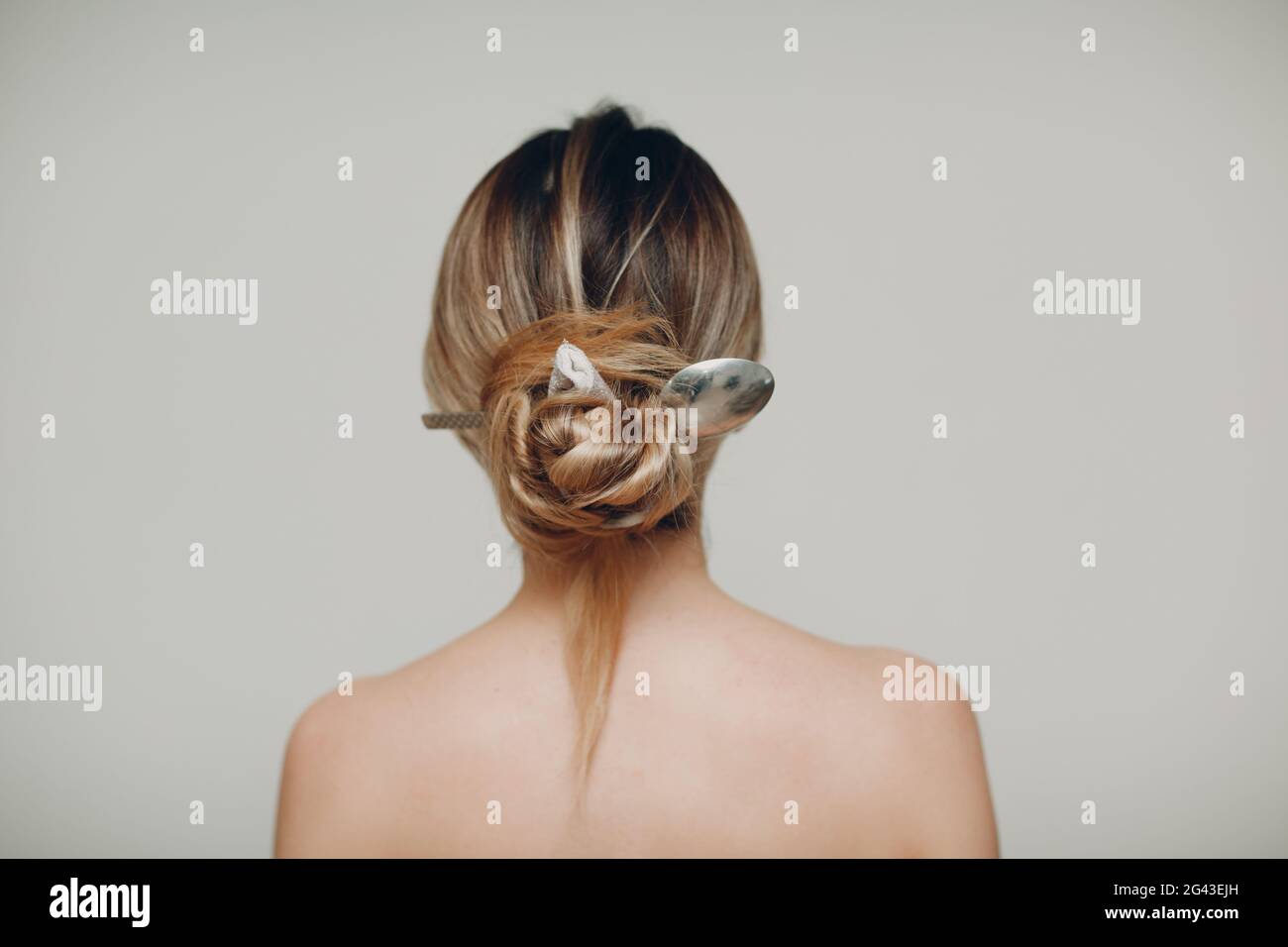 Frau mit Metalllöffel in ihrer Frisur Haare zurück Stockfoto