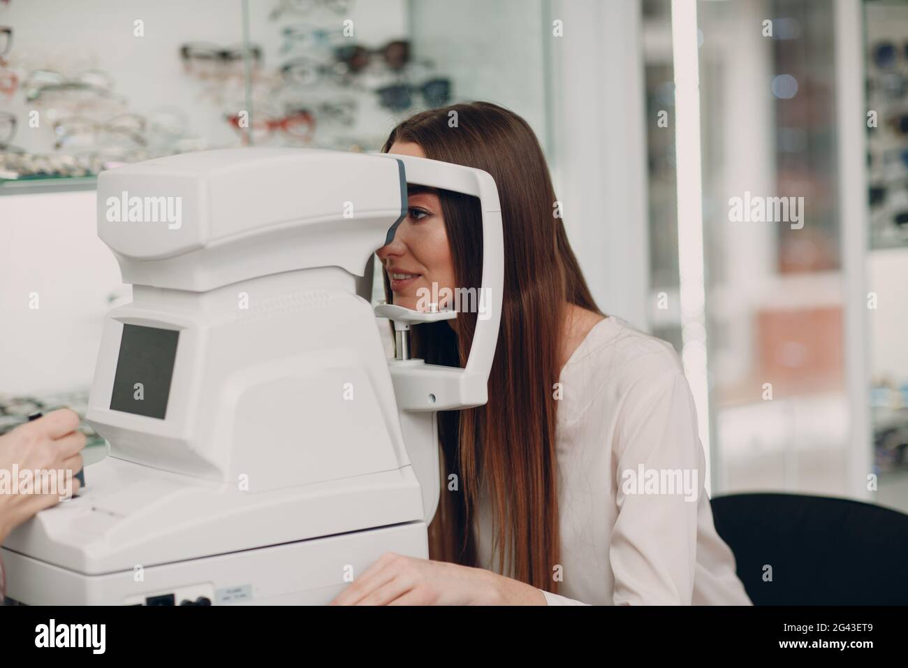 Eine Ärztin und Patientin, die einen ophthalmologischen Kontrolltest mit einem Refraktometer durchführen Stockfoto