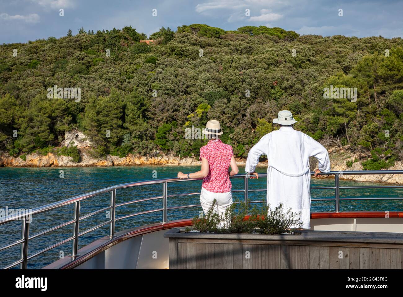 Paar auf Geländer des Kreuzfahrtschiffes mit Küste dahinter, in der Nähe von Kampor, Primorje-Gorski Kotar, Kroatien, Europa Stockfoto