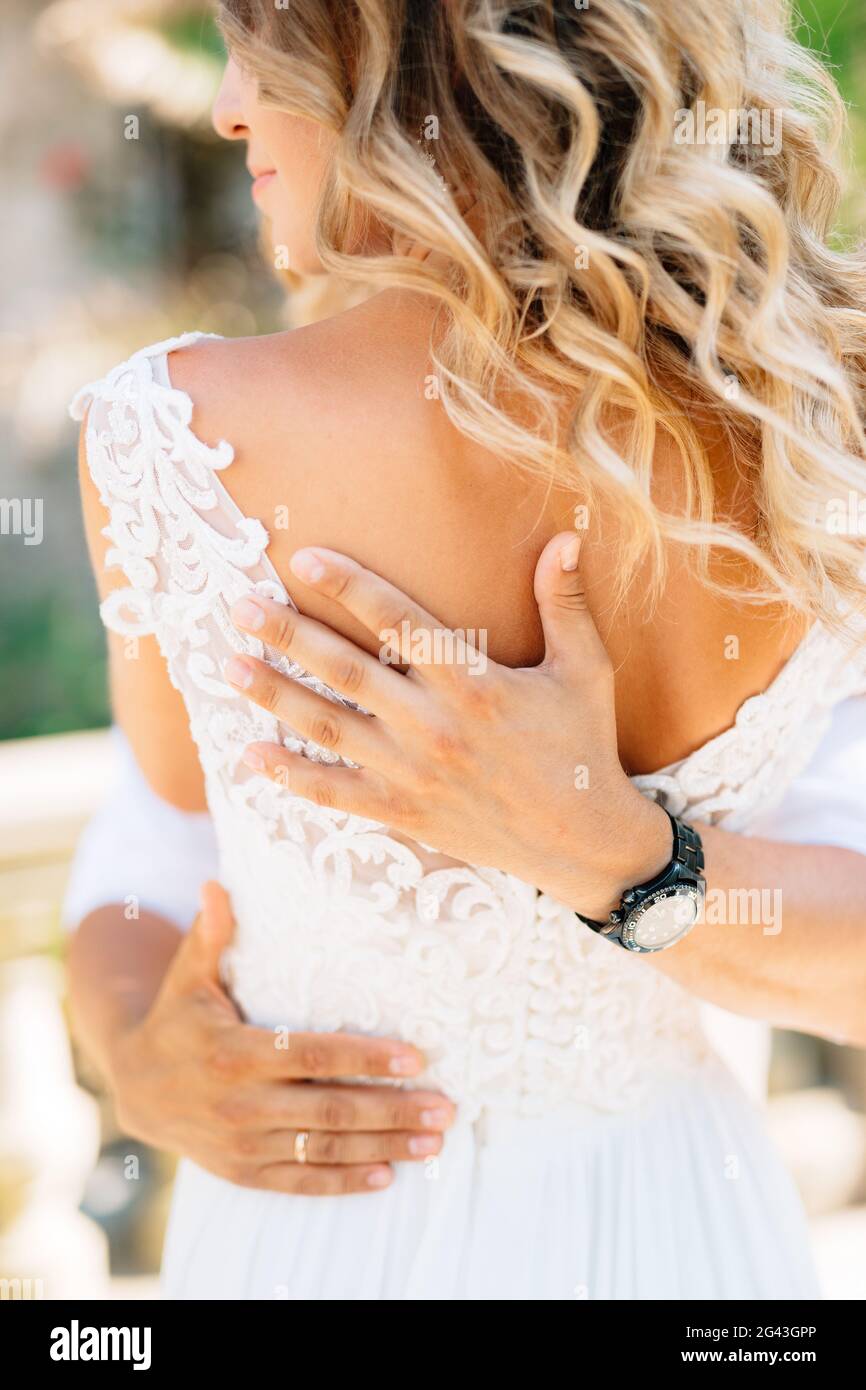 Der Bräutigam umarmt die Braut fest, die Hände des Bräutigams auf dem Rücken der Braut Stockfoto
