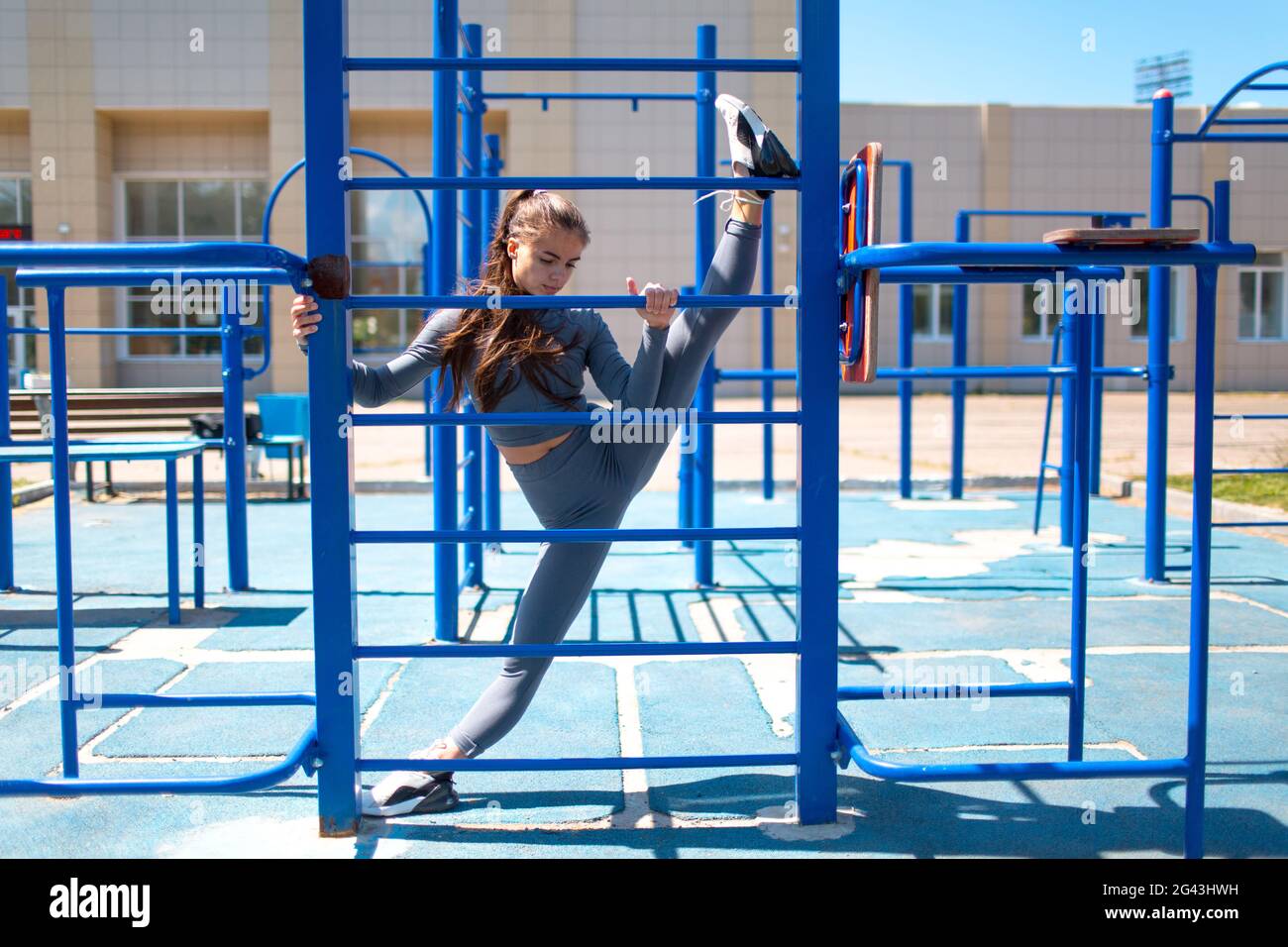 Junge schlanke Frau, die Garn macht, um die Beine zu strecken. Positive Mädchen tun die Splits im Freien. Stockfoto