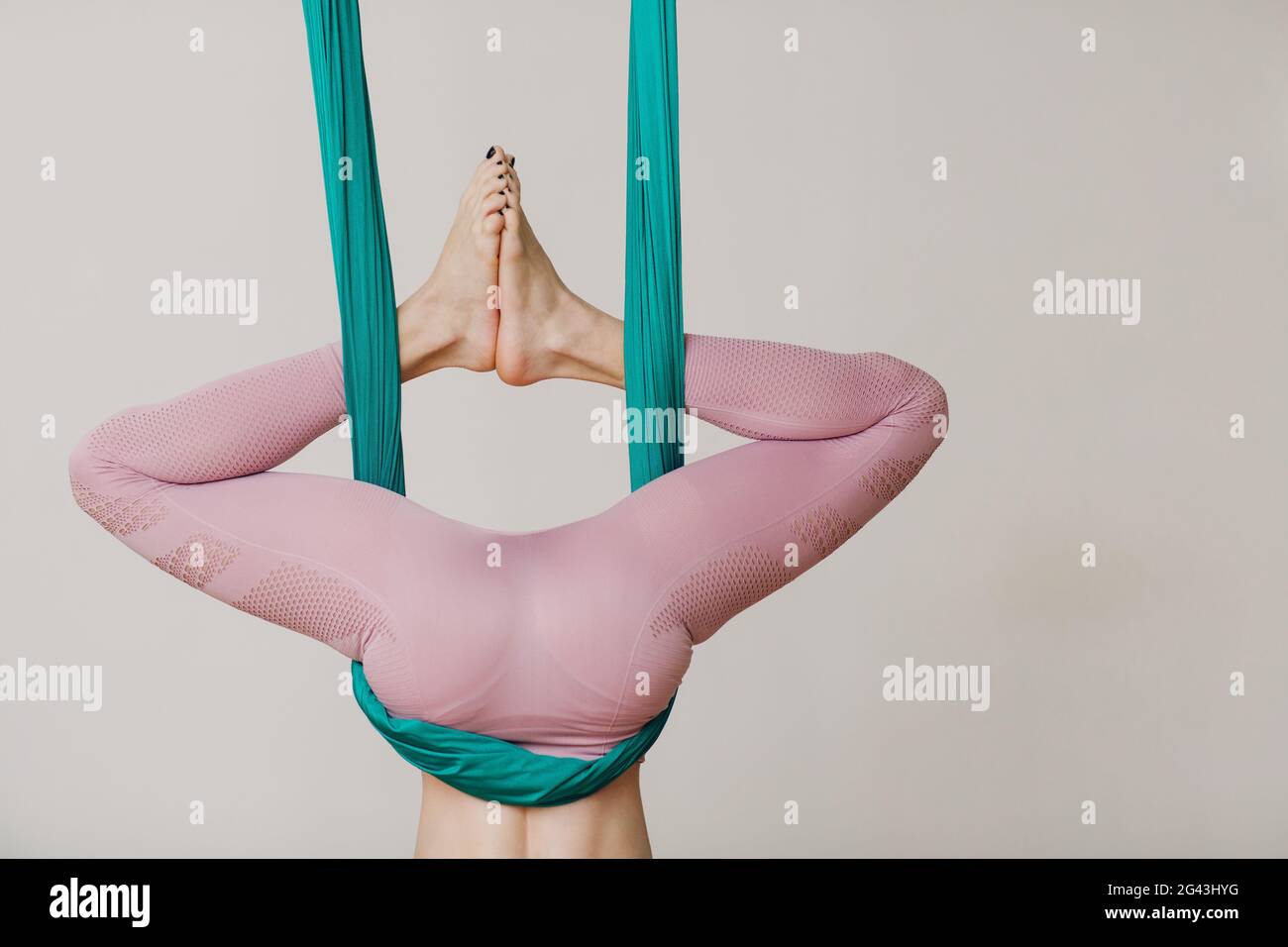 Luftbild Antigravitation Yoga Konzept. Frau, die Fliegenyoga im Anti-Schwerkraft-Yogastudio übt, das grüne Hängematte verwendet Stockfoto