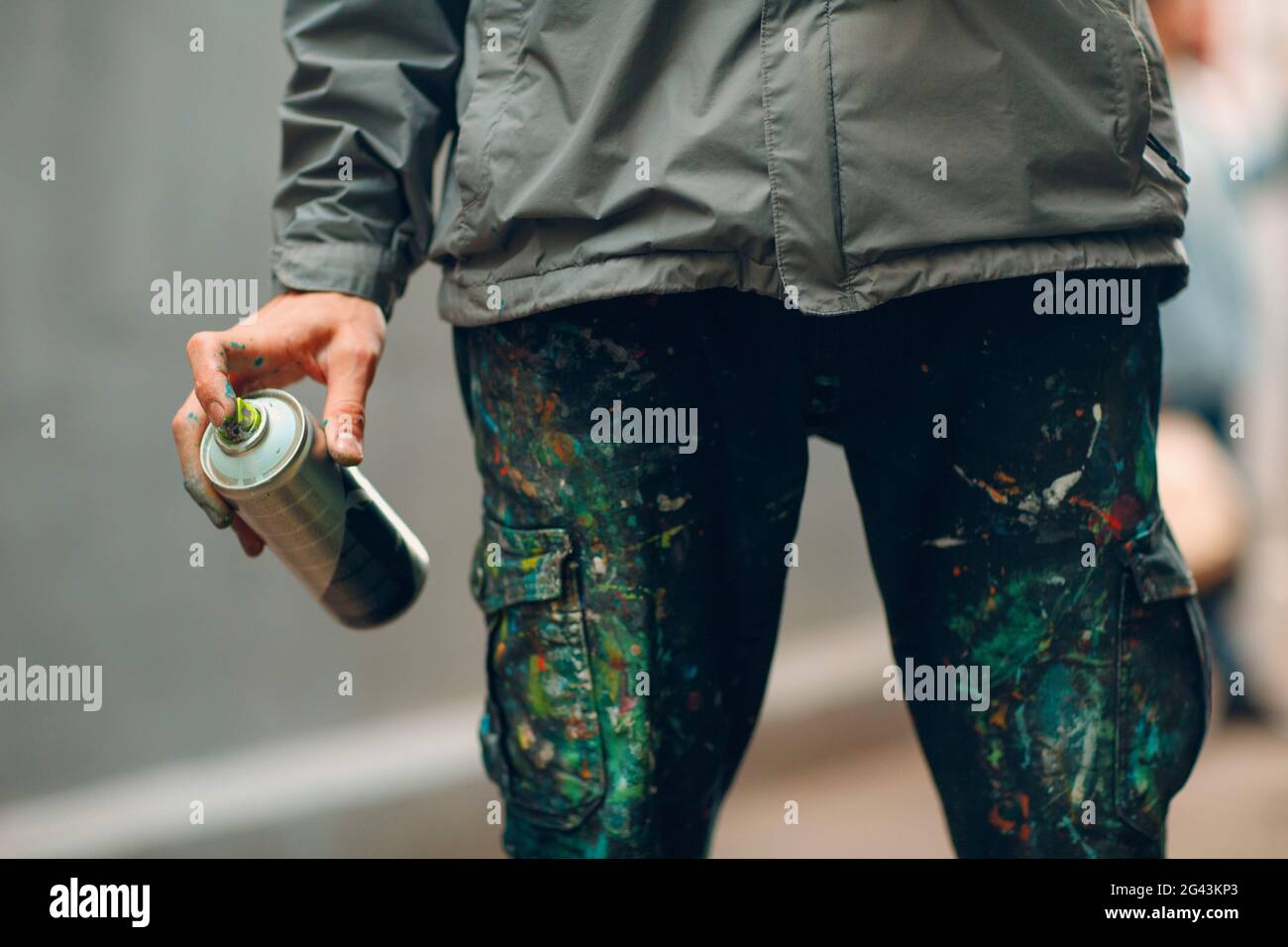 Graffiti Künstler in der Kleidung gebeizt mit Farbe Spraydose in der Hand Stockfoto